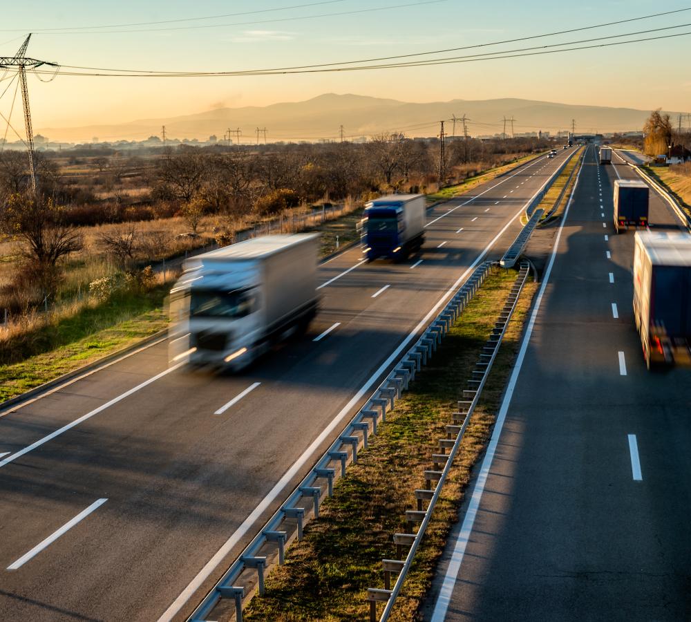 Camiones circulando por una autovía al atardecer