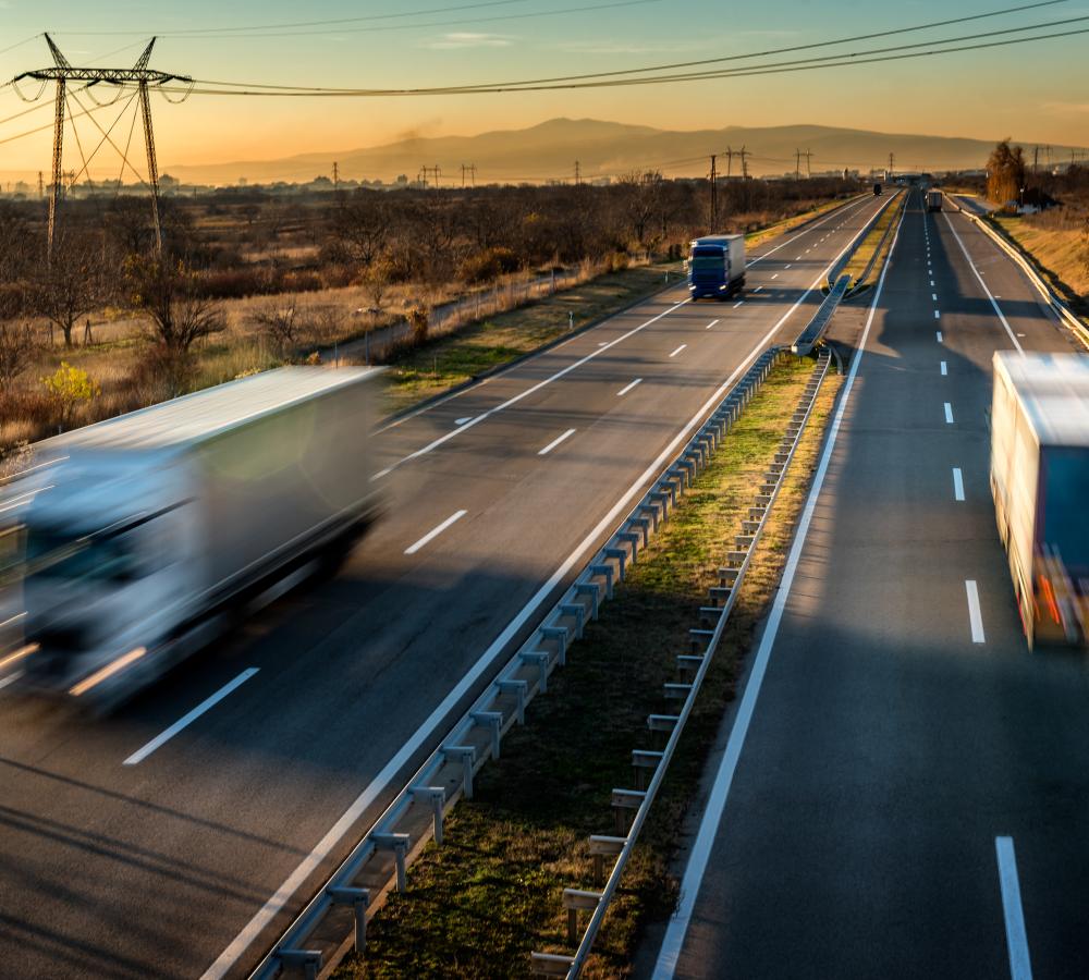 Camión en marcha por una autovía junto a torres eléctricas